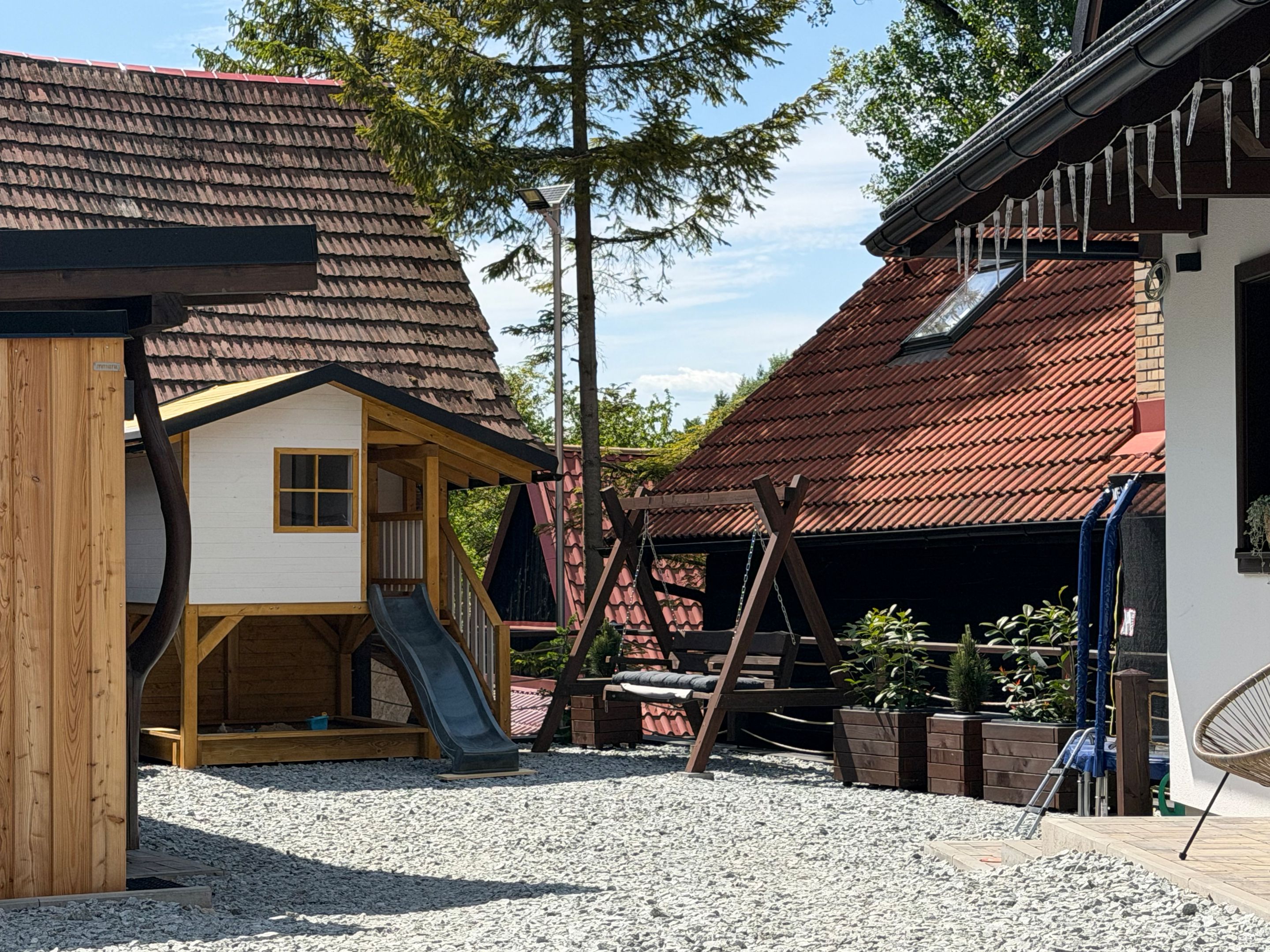 Dvor chaty s detským domčekom, šmýkačkou, hojdačkou a trampolínou